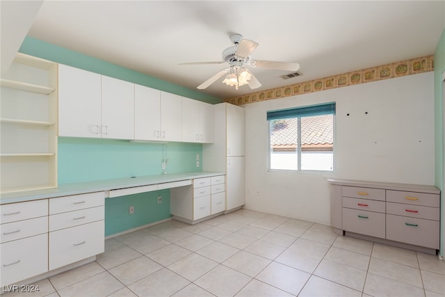 unfurnished office with ceiling fan, light tile patterned floors, and built in desk