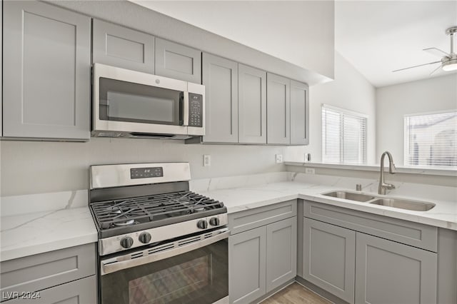 kitchen featuring light stone counters, light hardwood / wood-style flooring, sink, gray cabinetry, and stainless steel appliances