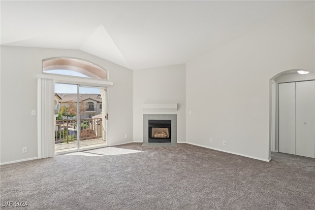 unfurnished living room featuring lofted ceiling, carpet, and a tiled fireplace