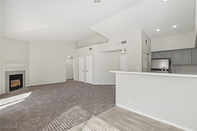 unfurnished living room with sink, a high ceiling, and light colored carpet