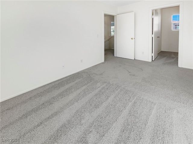 unfurnished bedroom featuring a walk in closet and light colored carpet