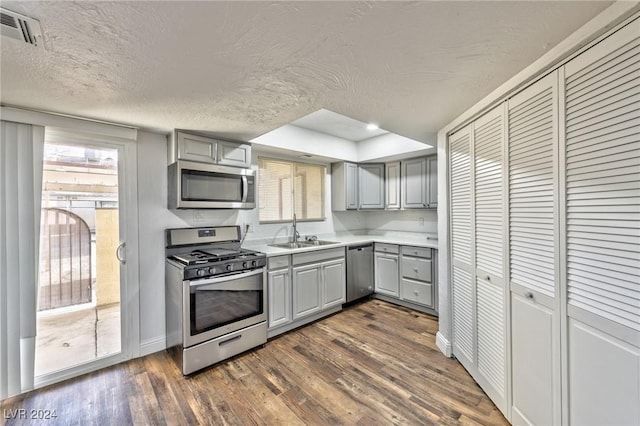 kitchen featuring a textured ceiling, stainless steel appliances, sink, gray cabinets, and dark hardwood / wood-style floors