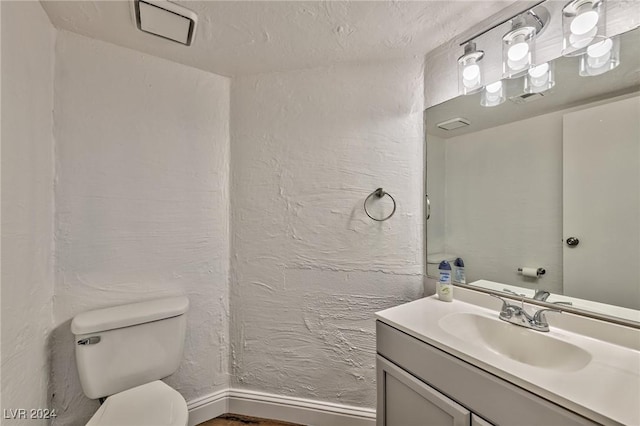 bathroom with a textured ceiling, vanity, and toilet