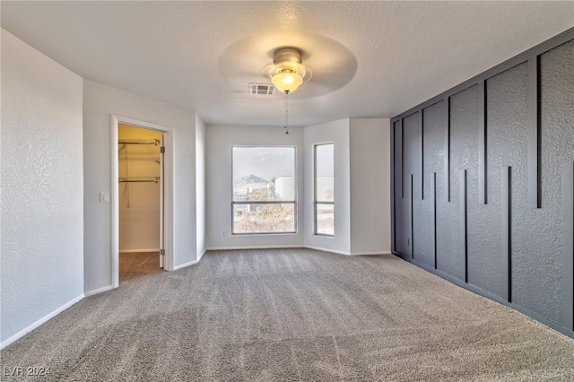 unfurnished bedroom featuring ceiling fan, carpet floors, and a textured ceiling