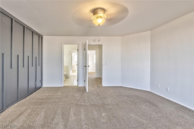 unfurnished bedroom with ceiling fan, a closet, light carpet, and a textured ceiling