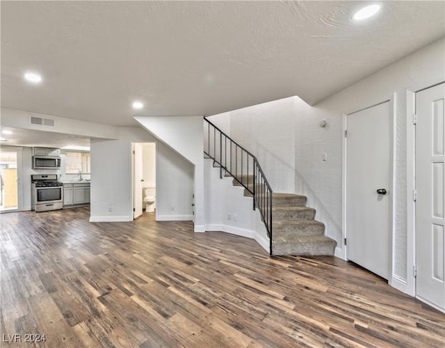 unfurnished living room featuring sink and dark hardwood / wood-style floors