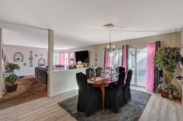 dining space with an inviting chandelier, light wood-type flooring, and a healthy amount of sunlight