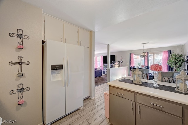 kitchen with a chandelier, white refrigerator with ice dispenser, decorative light fixtures, and light hardwood / wood-style floors