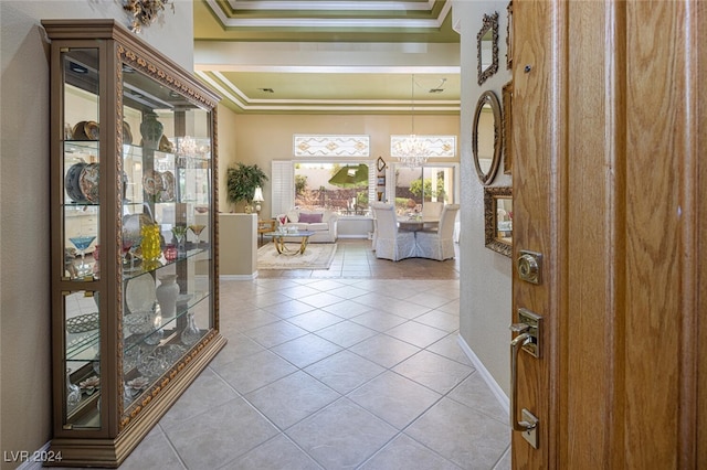 tiled entryway with a raised ceiling and crown molding