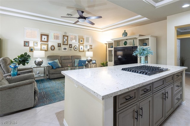 kitchen featuring stainless steel gas stovetop, ceiling fan, a kitchen island, and crown molding