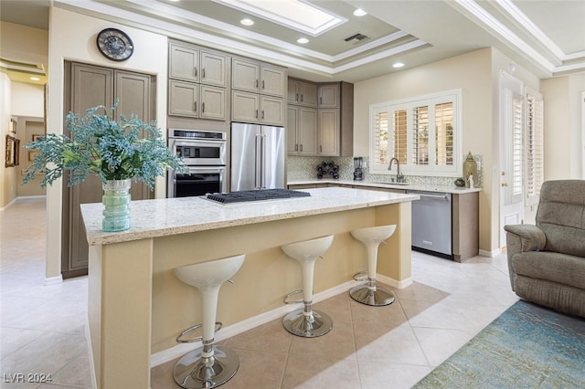 kitchen featuring sink, stainless steel appliances, a kitchen breakfast bar, a kitchen island, and ornamental molding