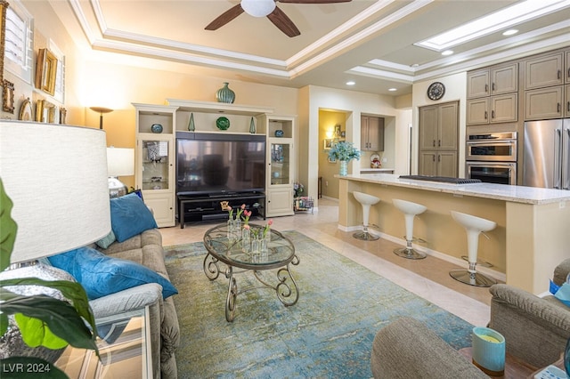 living room with a tray ceiling, ceiling fan, and ornamental molding