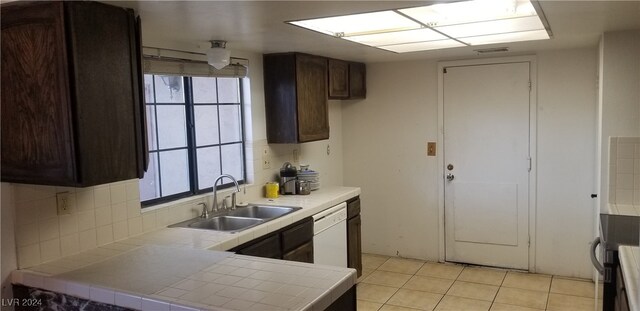 kitchen with decorative backsplash, dark brown cabinetry, sink, dishwasher, and tile counters