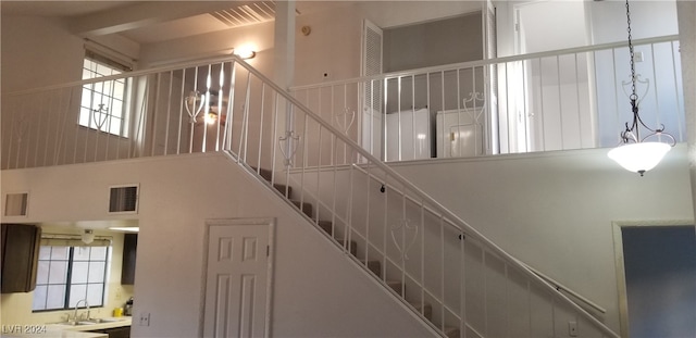 stairway featuring beamed ceiling, a towering ceiling, and sink