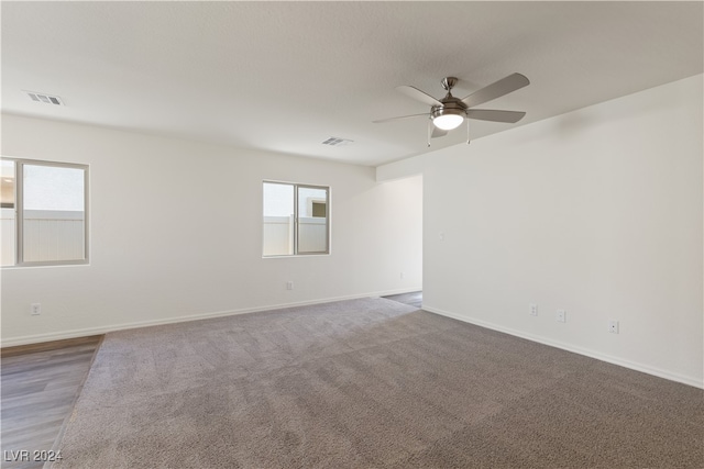 carpeted spare room with plenty of natural light and ceiling fan