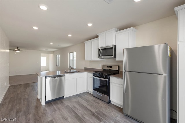 kitchen featuring light hardwood / wood-style flooring, kitchen peninsula, sink, white cabinetry, and appliances with stainless steel finishes