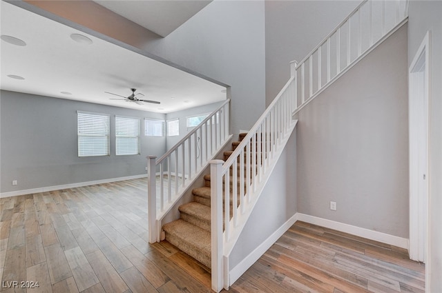 staircase with hardwood / wood-style flooring and ceiling fan