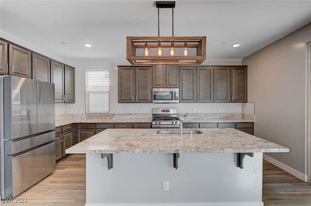 kitchen featuring appliances with stainless steel finishes, a kitchen breakfast bar, light wood-type flooring, and an island with sink