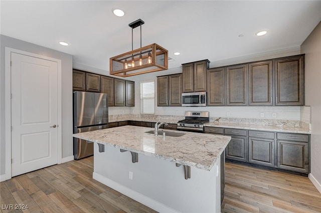 kitchen featuring appliances with stainless steel finishes, sink, light wood-type flooring, and decorative light fixtures