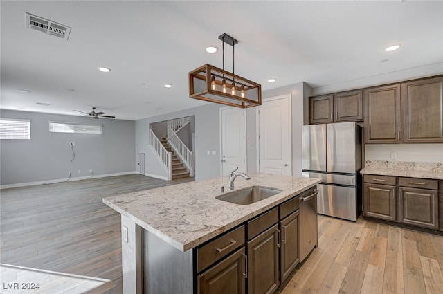 kitchen featuring sink, appliances with stainless steel finishes, a kitchen island with sink, and light hardwood / wood-style floors