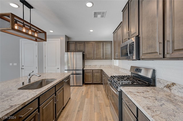 kitchen with light stone countertops, sink, dark brown cabinets, light hardwood / wood-style floors, and stainless steel appliances