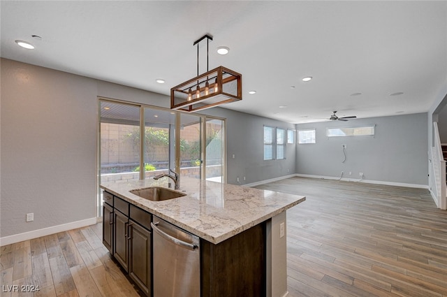 kitchen featuring light stone countertops, a kitchen island with sink, stainless steel dishwasher, light wood-type flooring, and sink