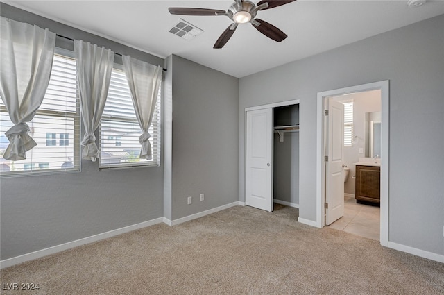 unfurnished bedroom with connected bathroom, light carpet, a closet, and ceiling fan