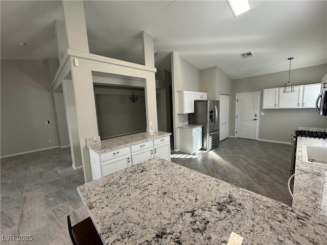 kitchen with pendant lighting, lofted ceiling, white cabinetry, stainless steel appliances, and light stone counters