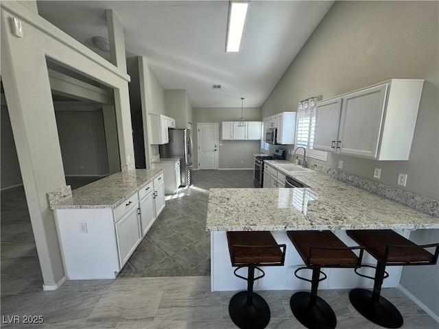 kitchen with appliances with stainless steel finishes, decorative light fixtures, white cabinets, and kitchen peninsula