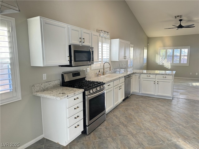 kitchen featuring sink, white cabinetry, stainless steel appliances, vaulted ceiling, and kitchen peninsula