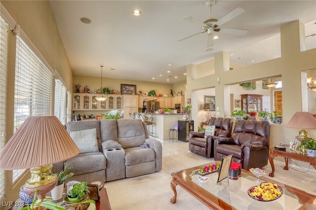 carpeted living room with ceiling fan and a high ceiling