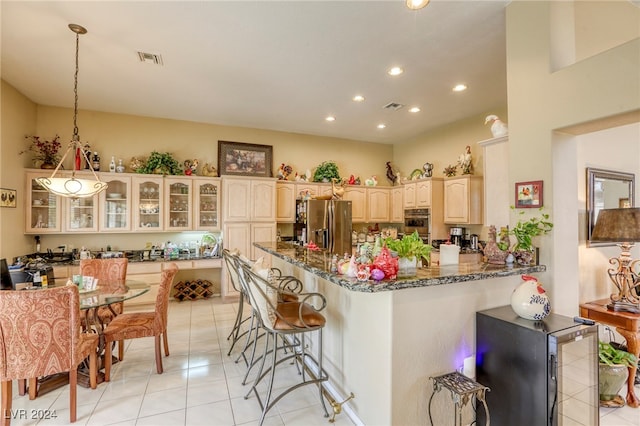 kitchen with dark stone countertops, light tile patterned floors, and stainless steel refrigerator with ice dispenser