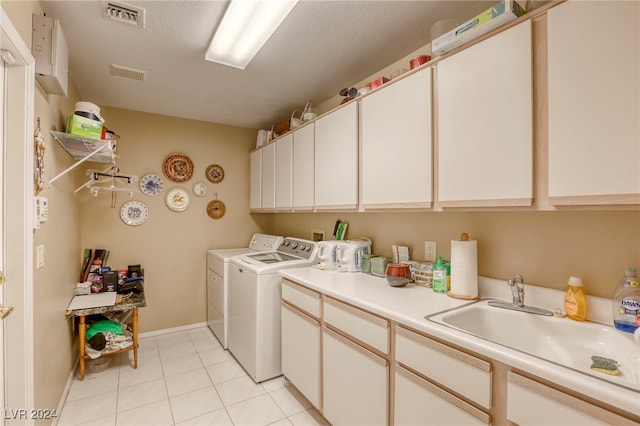 laundry area featuring sink, light tile patterned floors, washer and dryer, a textured ceiling, and cabinets