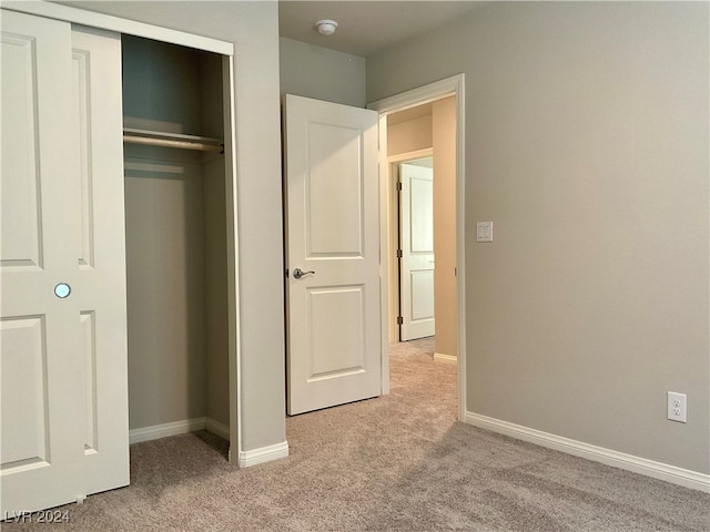 unfurnished bedroom with light colored carpet and a closet