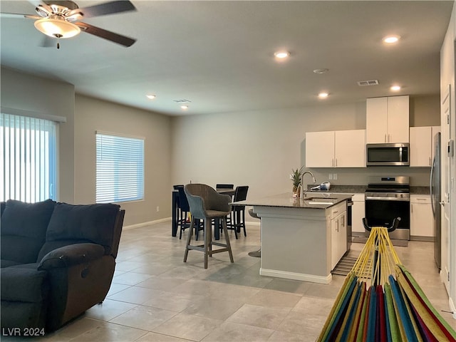 kitchen featuring white cabinets, a center island with sink, ceiling fan, appliances with stainless steel finishes, and sink