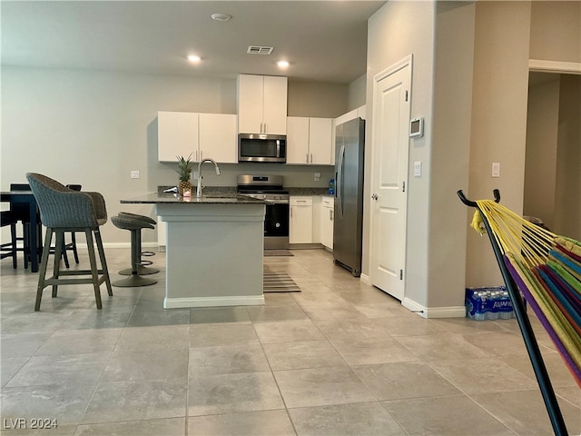 kitchen featuring sink, an island with sink, a kitchen breakfast bar, stainless steel appliances, and white cabinets