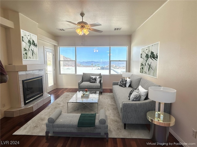 living room featuring hardwood / wood-style floors, ceiling fan, and a tile fireplace