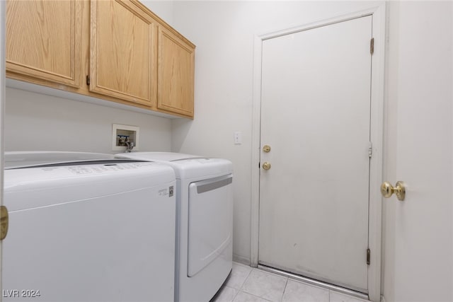 washroom with cabinets, washing machine and dryer, and light tile patterned floors