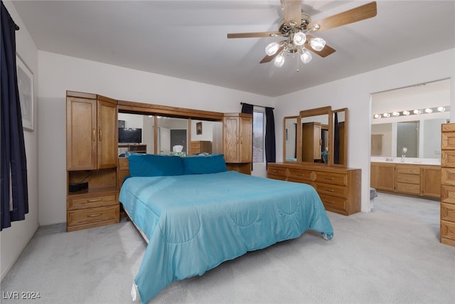 bedroom featuring ensuite bathroom, light colored carpet, and ceiling fan