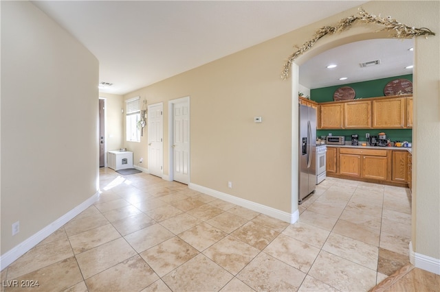 kitchen with stainless steel fridge with ice dispenser, light tile patterned floors, and white range