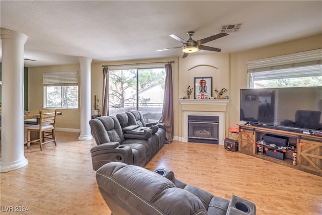 living room featuring ornate columns, light hardwood / wood-style floors, ceiling fan, and plenty of natural light