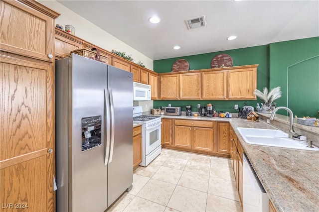 kitchen featuring light stone counters, sink, white appliances, and light tile patterned flooring