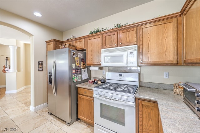 kitchen featuring decorative columns, white appliances, and light tile patterned flooring