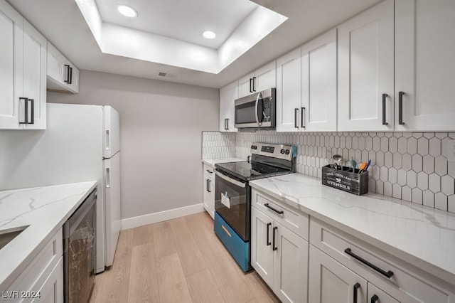 kitchen featuring black electric range, light stone counters, white cabinetry, and light wood-type flooring