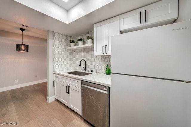 kitchen with decorative backsplash, white cabinets, stainless steel dishwasher, sink, and white refrigerator