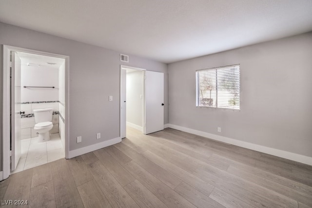 unfurnished bedroom with connected bathroom and light hardwood / wood-style flooring