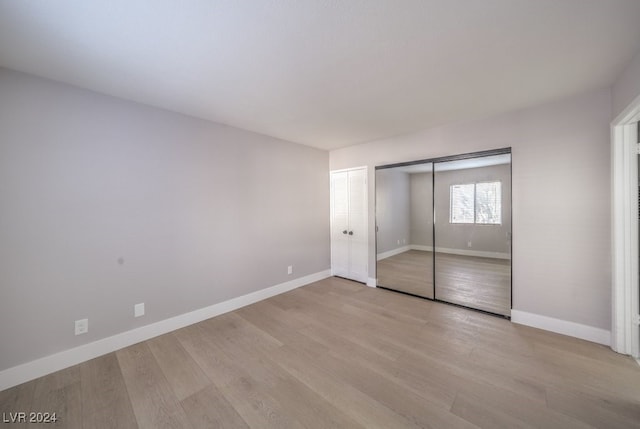 unfurnished bedroom with a closet and light wood-type flooring