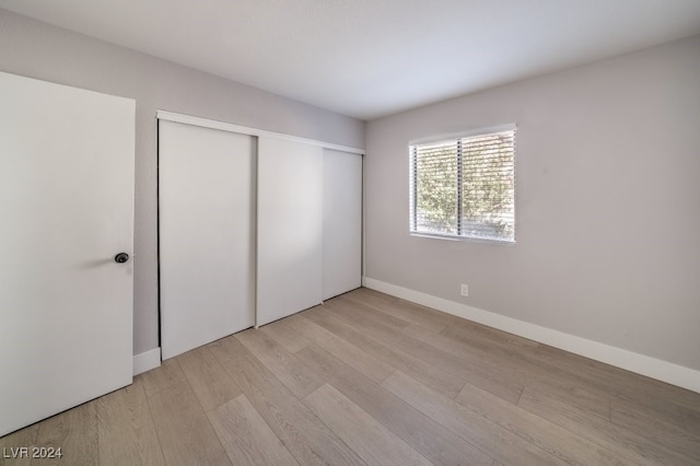 unfurnished bedroom with a closet and light wood-type flooring