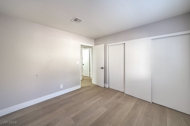 unfurnished bedroom with light hardwood / wood-style flooring and a closet