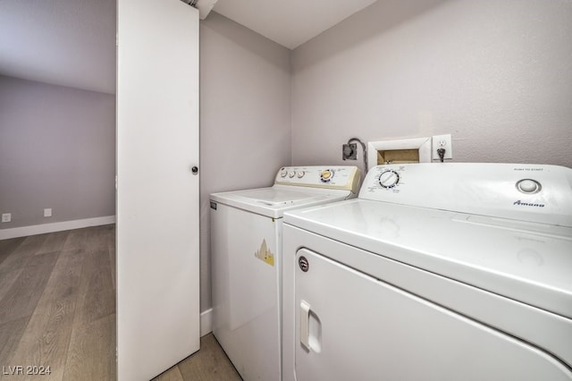 laundry area with light hardwood / wood-style floors and washer and clothes dryer